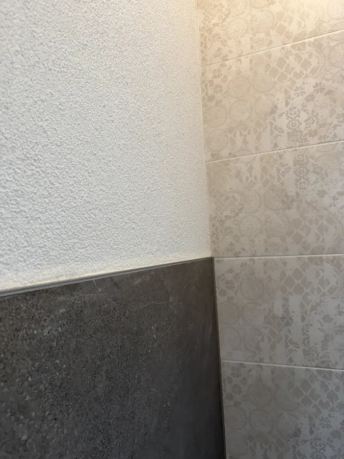 Wandfliesen mit Dekor neben grauer Steinoptik