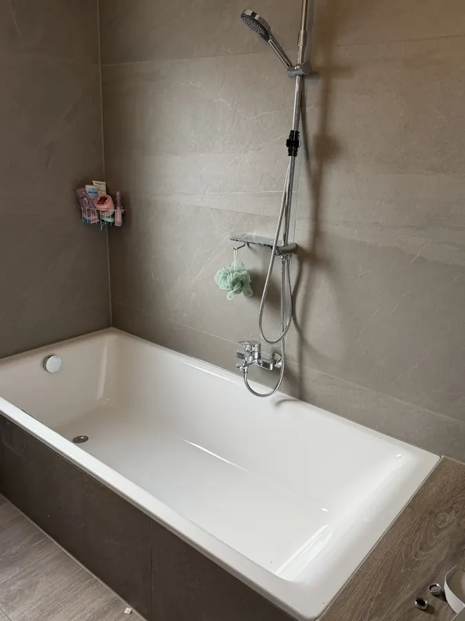 Badewanne mit grauen Wandfliesen in Steinoptik