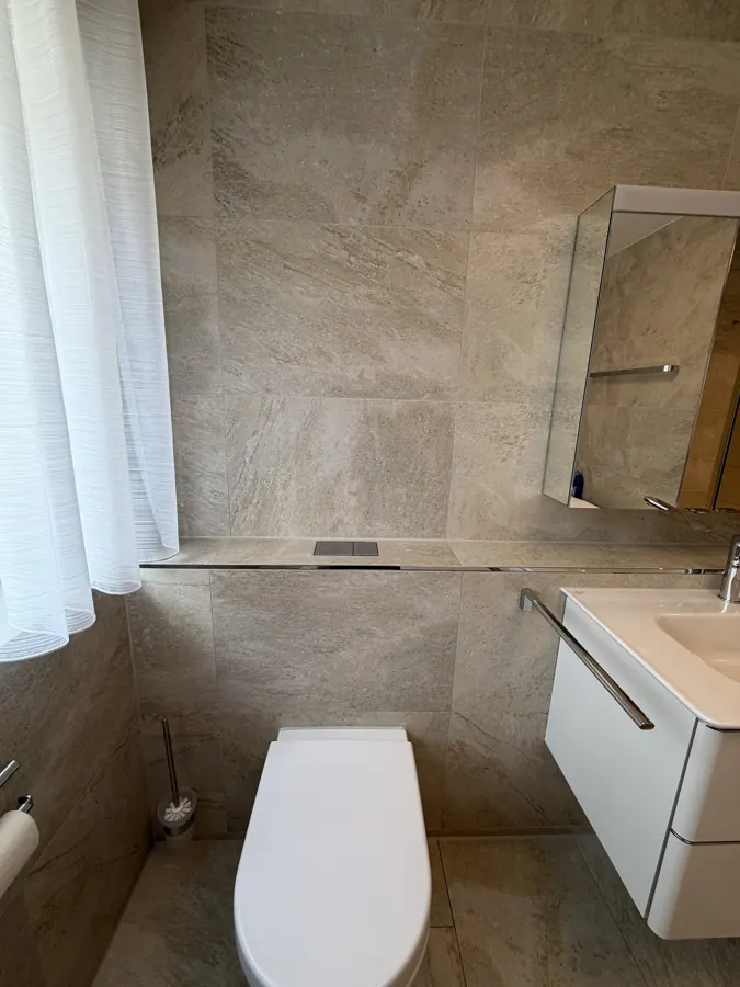 Gäste-WC mit Wandfliesen in Natursteinoptik und Ablage